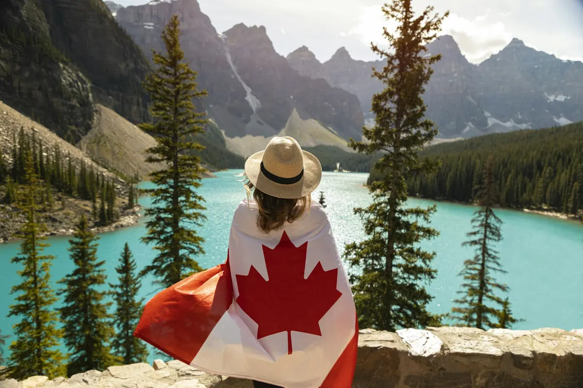 Newcomer carrying a Canadian flag outdoors