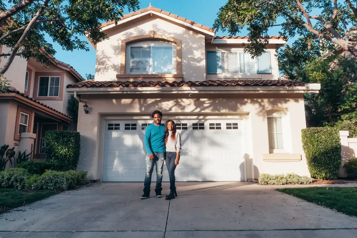 First-time home buyers standing outside their new house