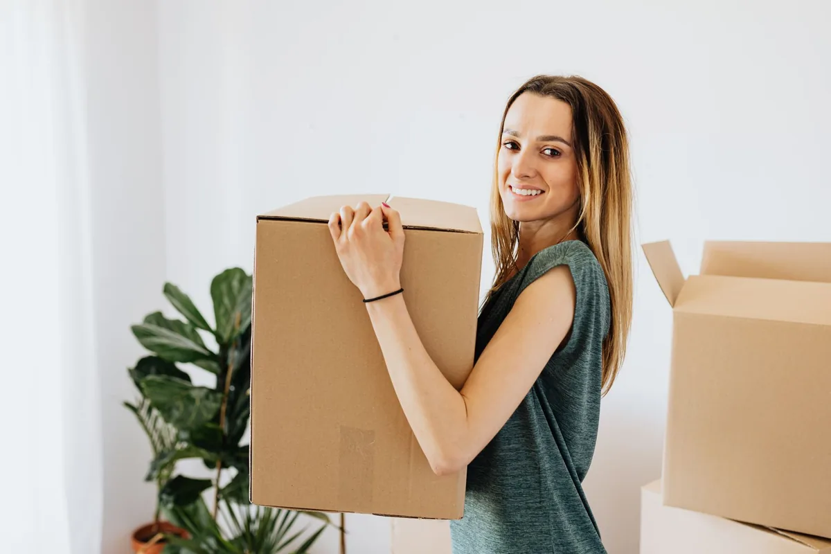 Woman carrying a moving box while relocating abroad