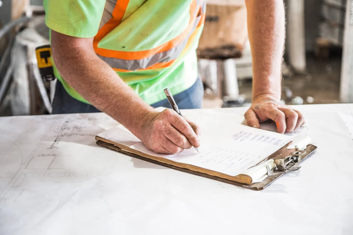 Construction worker writing job records on a clipboard