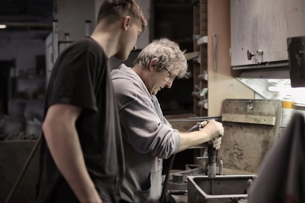Experienced tradesperson teaching an apprentice in a workshop