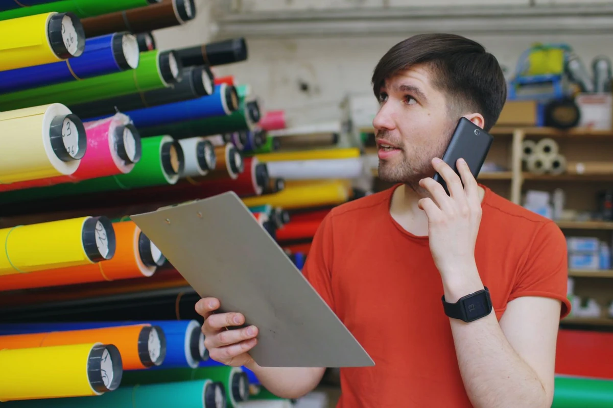 Worker checking stock in a warehouse of material rolls