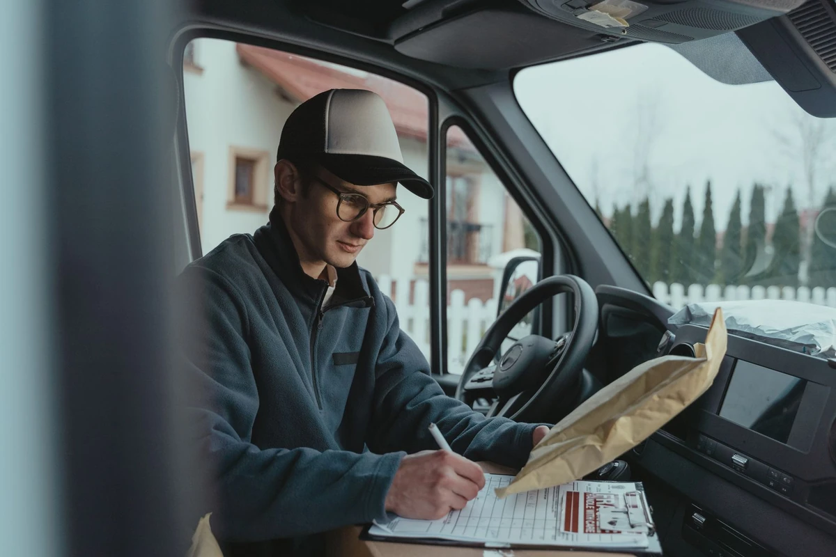Delivery driver recording shipment details inside a van