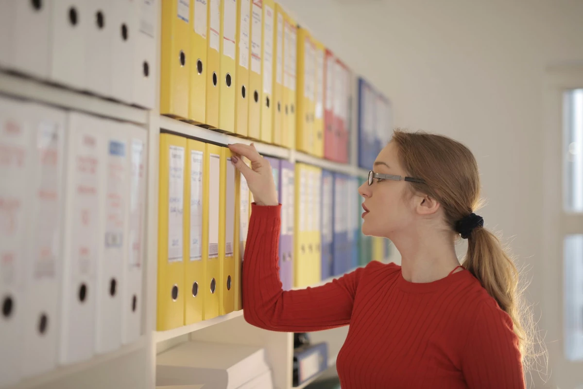 Office worker organising document binders on a shelf