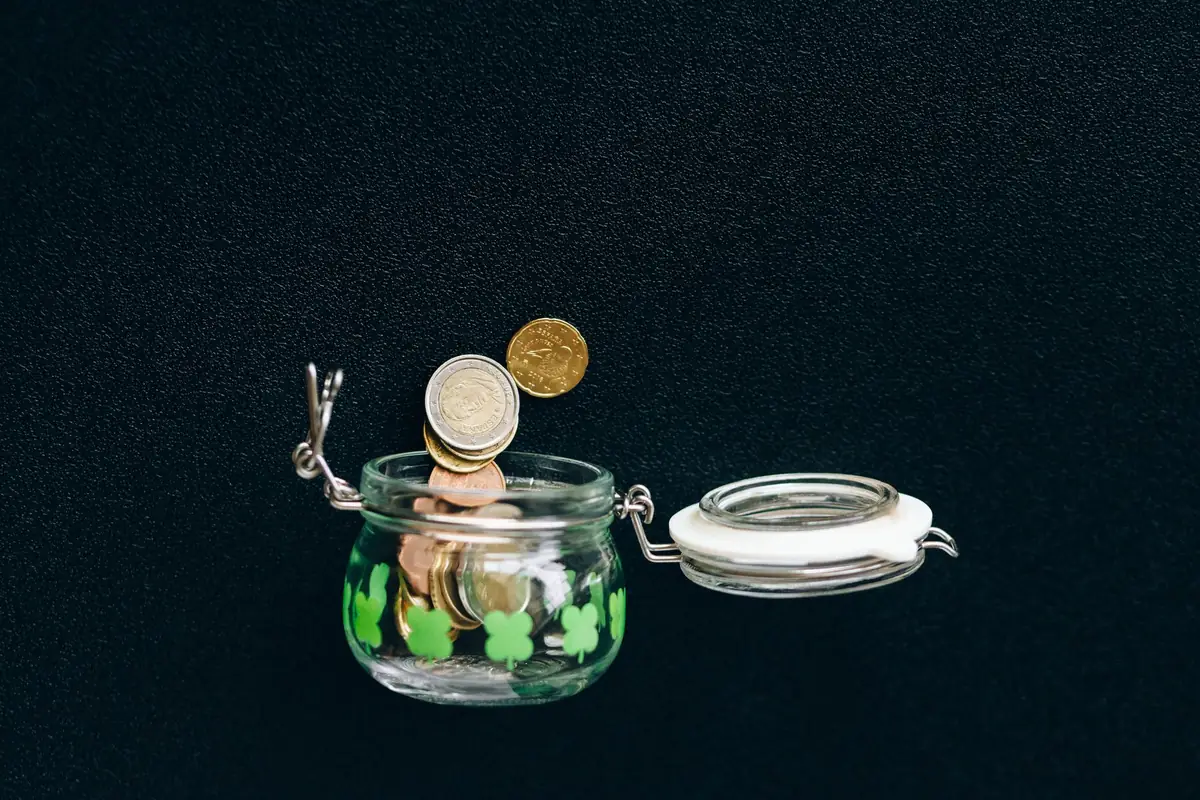 Coins falling into a clear glass jar