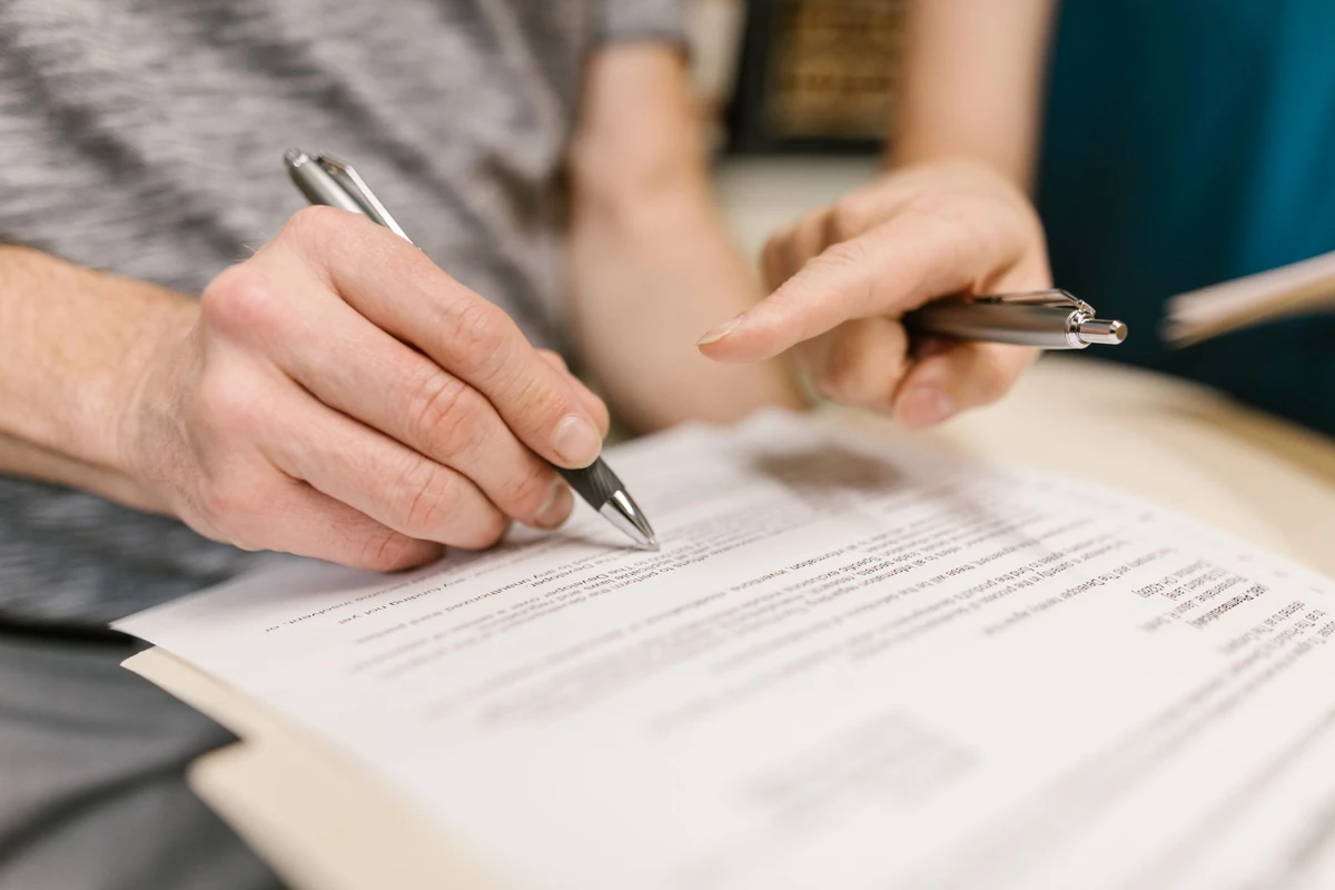 Two people reviewing and signing a legal document