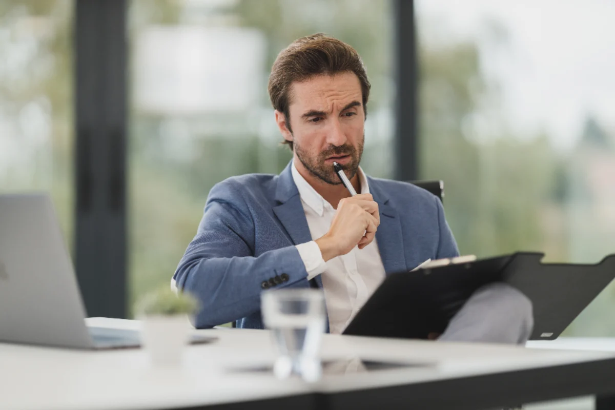 Business owner reviewing company assets and debts on a clipboard before dissolution