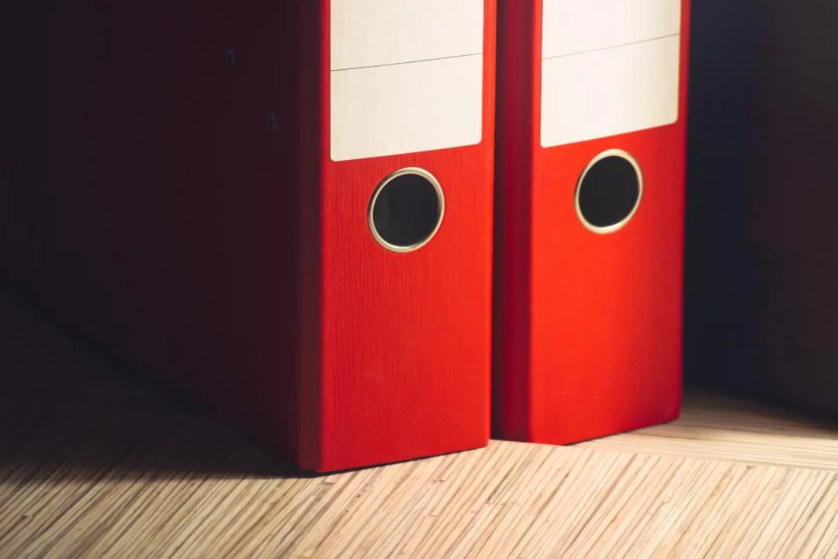 Red binders holding final corporate tax and payroll records