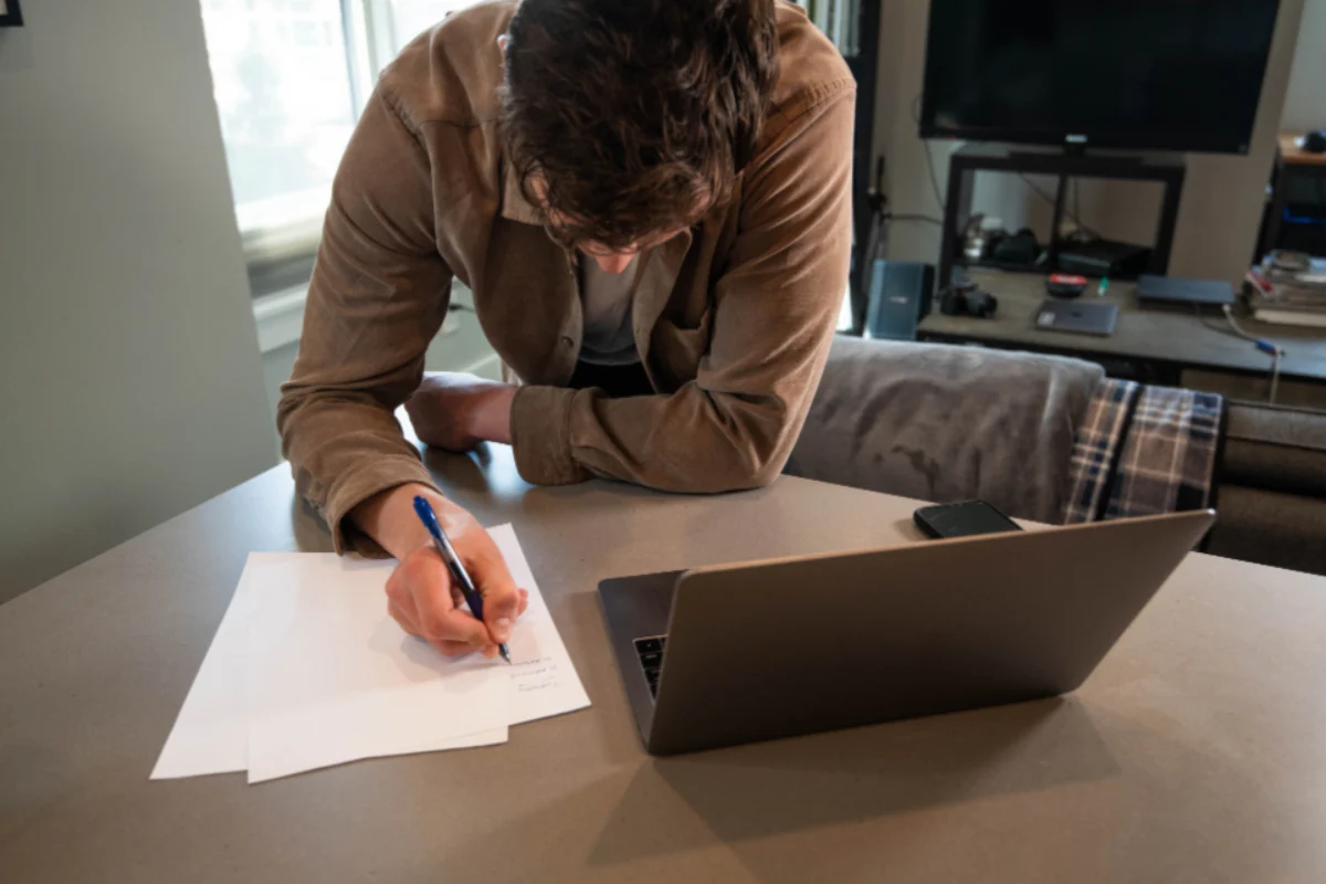 Director signing dissolution paperwork next to a laptop