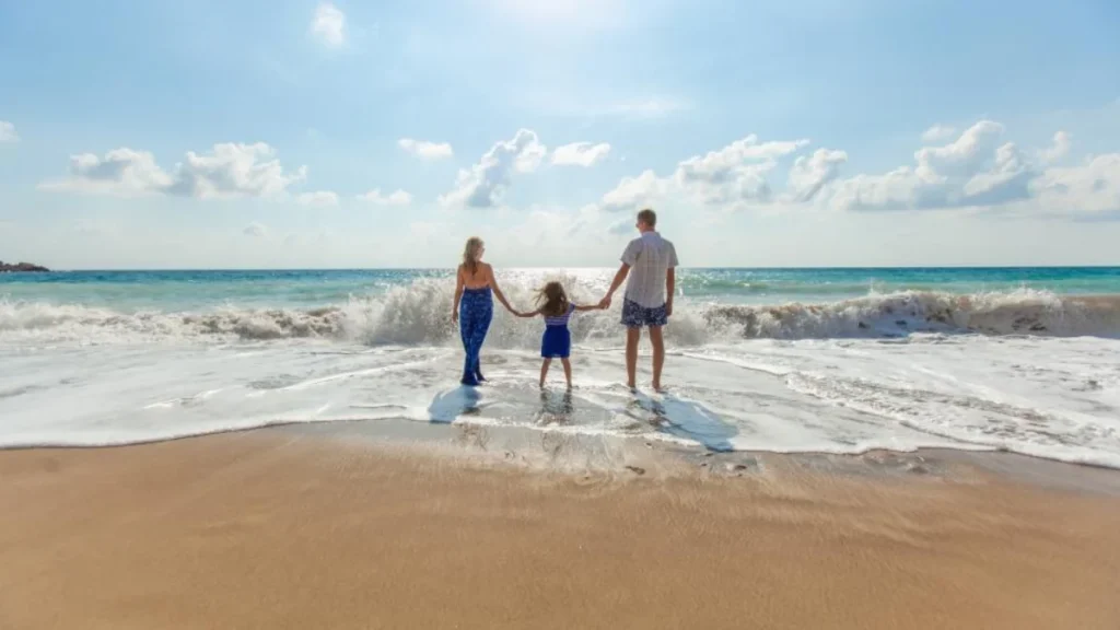 Family walking into the ocean on a beach vacation paid with vacation pay